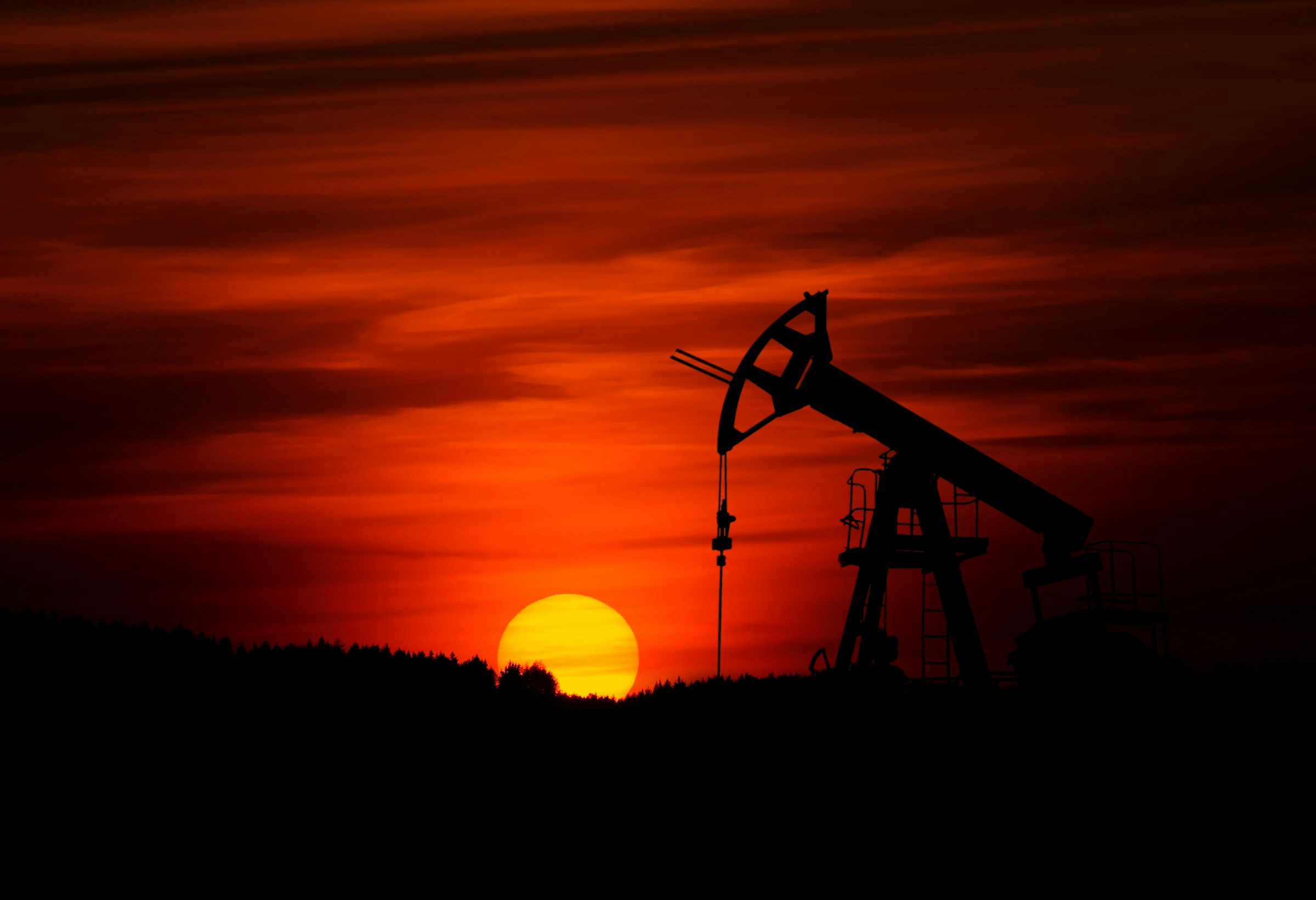 Oil field pumpjack silhouetted against a sunset sky